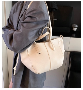 Detail of creamy white pebble grain leather tote bag with soft texture and twin handles