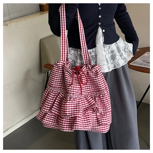 Detail view of red gingham tote bag featuring layered ruffles and drawstring rope closure