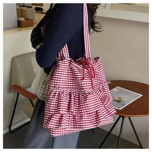 Detail of red and white checkered fabric tote bag with ruffled layers and a drawstring closure