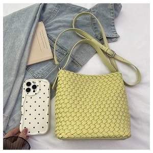 Close-up of beige woven texture and leather strap on a minimalist bucket handbag