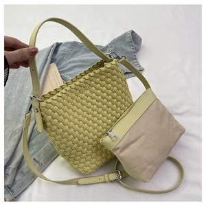 Detail of yellow woven bucket bag with leather strap and removable canvas inner pouch