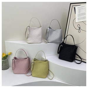 Collection of hand-woven bucket bags in various colors on a white minimalist display