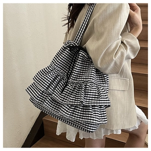 Close-up of black and white checkered fabric tote bag with ruffled layers and drawstring closure