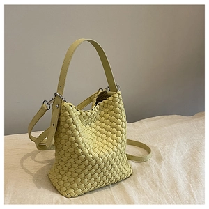 Detailed view of yellow woven bucket bag showing intricate texture and silver hardware