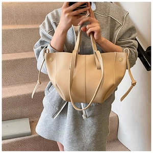 Detailed macro view of beige lychee leather tote bag with side drawstring and metal buckle