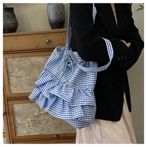 Detail of blue and white checkered fabric tote bag with ruffled layers and drawstring closure