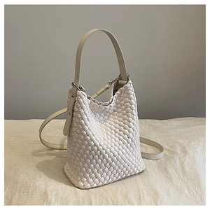Close-up of the woven bucket bag detail showing the cream white texture and leather strap