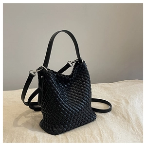 Detail of black woven leather bucket bag with silver metal buckle and adjustable strap