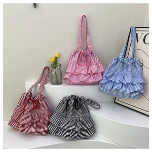 Detail view of four colorful checkered drawstring tote bags with layered ruffle trim on display