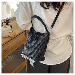 Detail of black woven bucket bag featuring elegant white lace trim and silver hardware
