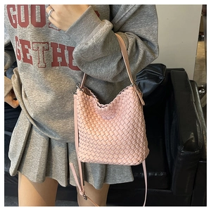 Detail of pink woven leather bucket bag with adjustable strap worn by model