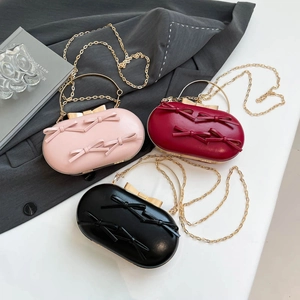 Three elegant evening clutch bags with bow knots in pink, red, and black with gold handles