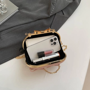 Pink bow evening clutch with gold chain strap showing interior space for phone and makeup