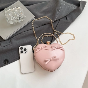 Pink heart-shaped evening bag with bow detail and golden metal chain strap