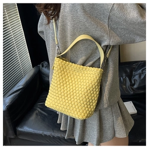 Detail of yellow woven texture bucket bag with leather strap and metallic buckle