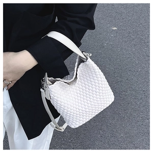 Outdoor shot of white woven bucket bag showing detailed texture and silver metal hardware