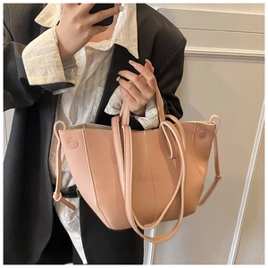 Detail der aprikosenfarbenen Tragetasche aus genarbtem Leder mit minimalistischem Trapezdesign
