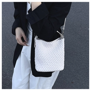Close-up of white woven bucket bag showing detailed texture and silver buckle hardware
