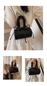 Detail of heart-quilted black Boston bag with scrunchie handle and metal chain