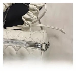 Close-up of heart quilted texture and silver hardware on white boston handbag