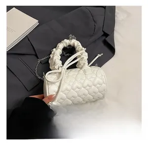 Detail view of heart-quilted white boston bag with pleated handle and chain strap