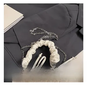 Detail view of a white quilted pillow bag featuring a cloud-style ruched handle and silver chain