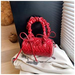 Detail of red heart-stitched quilted pillow bag with ruffled handle and silver chain