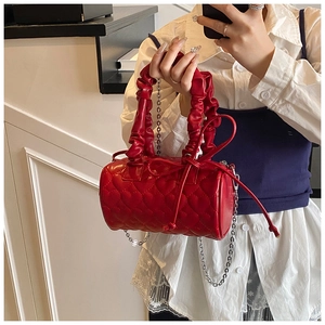 Detail of red cylinder bag with heart quilting, ruched handle and silver chain strap