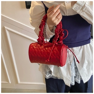 Close-up of red cylindrical handbag with heart-quilted pattern and ruffled handle detail