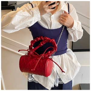 Model showing a red cylinder bag with heart quilting and ruffled handle detail