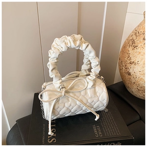 Detail of white heart-quilted cylinder handbag with ruched handle and bow accessory
