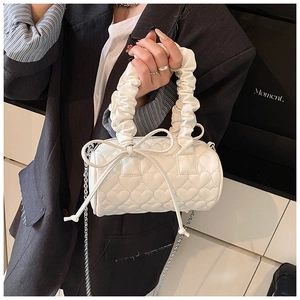 Detail of white heart-quilted cylinder bag with scrunchie handle and silver chain