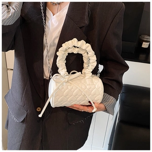 Detail of white quilted heart pillow bag with pleated handle and silver chain strap