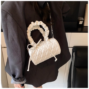 Detail of white heart-quilted cylinder bag with ruffled handle and silver chain strap