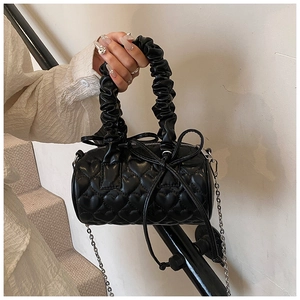 Detail of heart-quilted black pillow bag with pleated handle and bow decoration