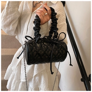 Detail of black heart-quilted boston bag with ruffled handle and bow drawstring ornament