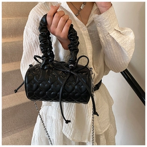 Detail of heart quilted black cylinder bag with scrunchie handle and silver chain strap