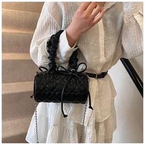 Detail of black quilted leather handbag featuring heart patterns and bow drawstring
