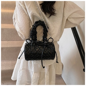 Close-up of heart quilted Boston bag featuring ruffled handle and black ribbon bow detail