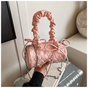 Detail of pink cylinder bag with heart quilting, cloud handle, and ribbon bow decor