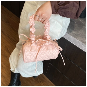 Detail of pink cylindrical Boston bag featuring heart quilting and a ruffled cloud handle