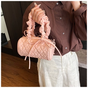 Close-up of pink heart-quilted cylinder bag with ruffled handle and bow detail