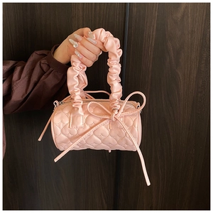 Close-up of pink heart-quilted cylinder handbag featuring scrunchie handle and bow detail