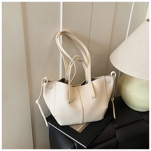 Detail of cream white leather shoulder bag with pebbled texture and drawstring on a side