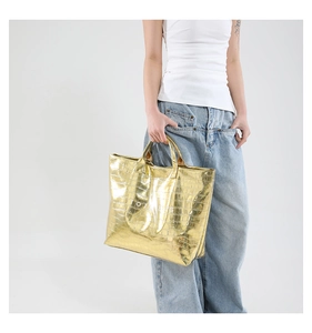 Close-up of golden metallic crocodile pattern texture on a large tote bag for women