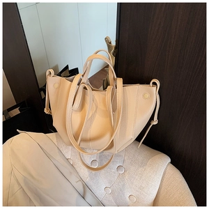 Nahaufnahme einer beigen Shopper-Tasche aus Leder mit Kordelzug auf einem weichen Sessel