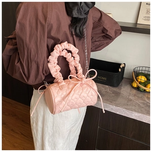 Close-up of pink quilted heart bag with ruffled handle and elegant bow detail