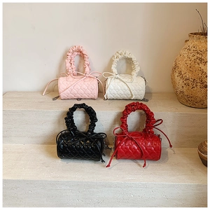 Detailed view of four colorful mini cylinder bags with heart quilting and ruched handles