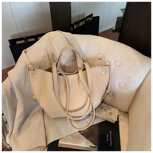Detailansicht der beigen Tote Bag aus Litschileder mit Trapezstruktur auf einem Sofa