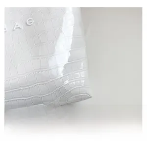 Close-up of white tote bag with crocodile pattern and BAG lettering detail